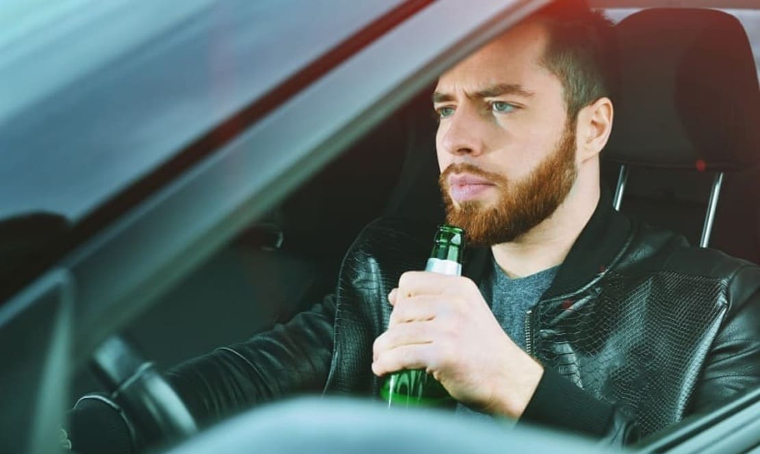 Мужчина  бутылкой пива за рулем